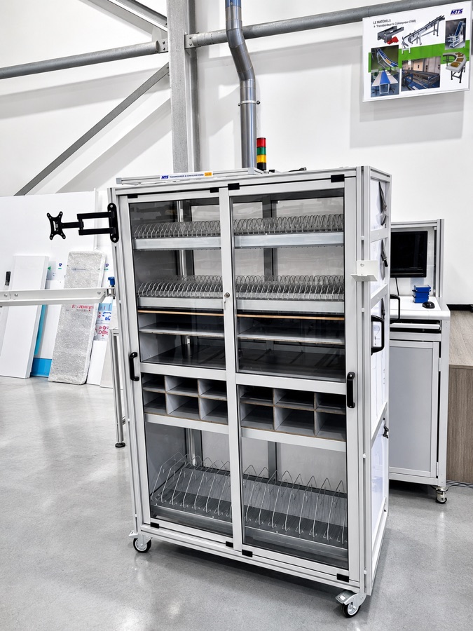Armoire de stockage mobile MTS en profilés aluminium : portes vitrées coulissantes, étagères à séparateurs, colonne lumineuse et bras support d'écran.